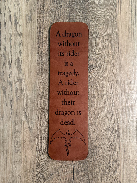 A brown, rectangular leather bookmark with rounded corners. Laser-engraved with a quote from Fourth Wing: "A dragon without its rider is a tragedy. A rider without their dragon is dead." A laser-engraved outline of a dragon is below the text.