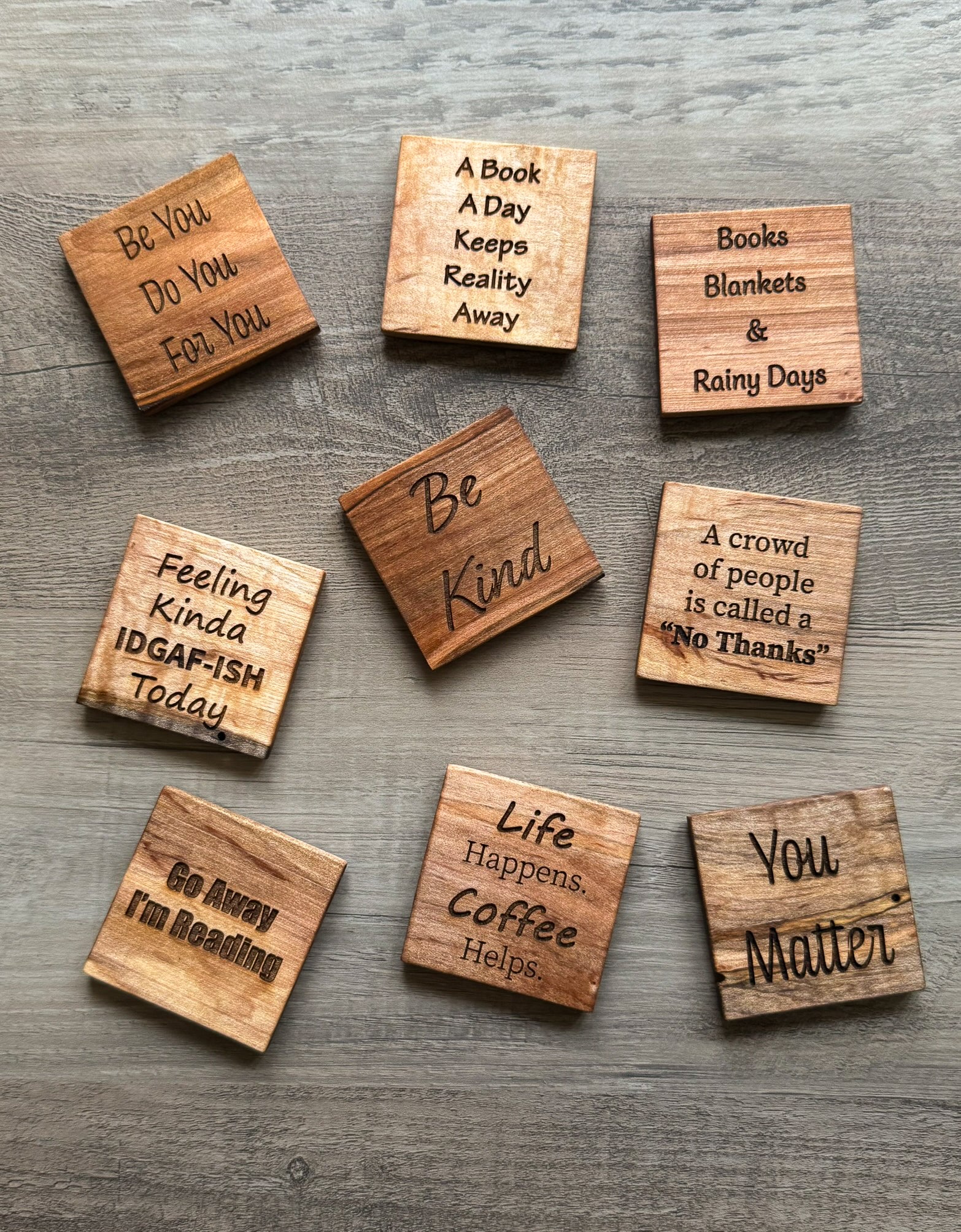 Wooden magnets with motivational phrases on a wooden surface